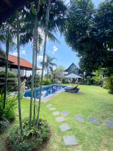 a resort yard with a swimming pool and palm trees at Kubu Di Omo Villas in Munggu