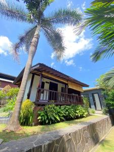 a house with a porch and a palm tree at Kubu Di Omo Villas in Munggu