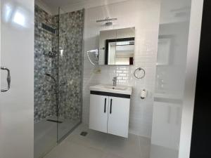 biała łazienka z umywalką i prysznicem w obiekcie Şirin Garden Ayvalık w mieście Ayvalık