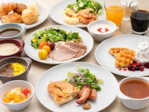 een tafel met witte borden met voedsel erop bij Hotel Villa Fontaine Kobe Sannomiya in Kobe