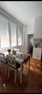 een witte tafel en stoelen in een kamer met ramen bij Apartment Major in Belgrado