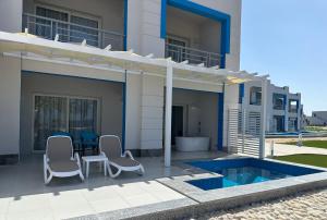 uma casa com um pátio com cadeiras e uma piscina em Casa Blue Resort em Marsa Alam