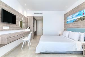 a bedroom with a white bed and a tv on a wall at Atlantica SunGarden Beach in Ayia Napa
