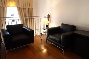 a living room with two black chairs and a lamp at Hotel San Rocco in Muggia
