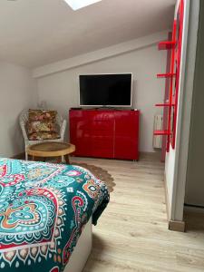 um quarto com uma cama e uma televisão num armário vermelho em Casa Vacacional La Coruña em Culleredo