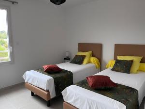 Cette chambre comprend 3 lits avec des oreillers jaunes et rouges. dans l'établissement Val des Bruyères - gîte 15mn Pézenas avec terrasse et cour close - Parking privatif securisé - Wifi gratuit, à Néffiès
