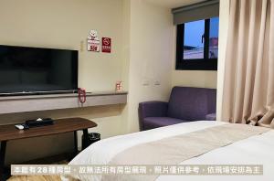 ein Hotelzimmer mit einem Bett und einem Flachbild-TV in der Unterkunft Dazz Inn in Taichung