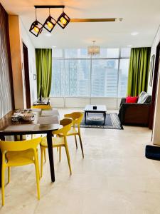 uma sala de estar com uma mesa e cadeiras amarelas em Vortex suites klcc by Yashrib em Kuala Lumpur