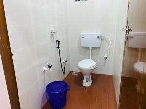 a bathroom with a toilet and a blue trash can at Bethel inn in Mananthavady