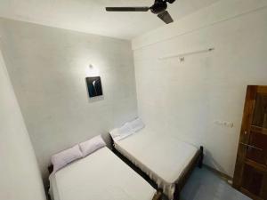 Habitación pequeña con 2 camas y ventilador de techo. en Bethel inn, en Mananthavady