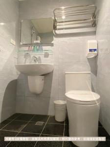 a white bathroom with a toilet and a sink at Dazz Inn in Taichung
