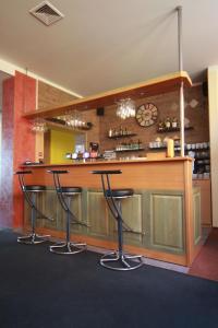 un bar con tres taburetes en una habitación con reloj en hotel Sádek, en Díly