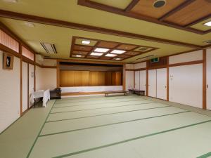 an empty room with a large room with tables and benches at Tabist Sakura no Yakata Hotel in Fuefuki