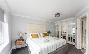 1 dormitorio con 1 cama blanca grande con almohadas amarillas en Loveliest Homes Paignton - Casa Marina - 3 bed, 2 bathroom house, balcony, parking en Paignton