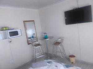 a kitchen with a table and two stools and a television at MOFFAT GUEST HOUSE in Randfontein