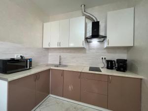 a kitchen with white cabinets and a sink and a microwave at Arcadia Adelina in Odesa