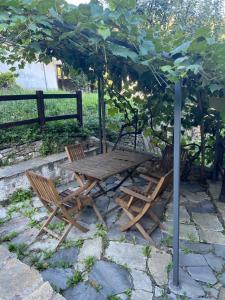 una mesa de madera y dos sillas bajo una sombrilla en Casa Esterina, en Garessio