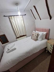 a bedroom with a white bed with a pink headboard at Two Bedroom Grade ll Cottage At AZ Luxury Stays Honey Horsefield With WiFi And Free Parking in Hundon