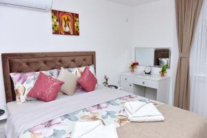 una camera da letto con un letto con cuscini rosa e viola di Apartmani Simić a Kuršumlija