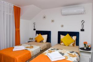 2 letti in una camera con arancione e bianco di Apartmani Simić a Kuršumlija