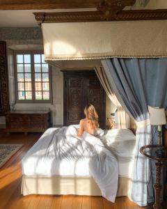 een vrouw die op een bed ligt bij Le château de Bonnemare - Bed and breakfast in Radepont