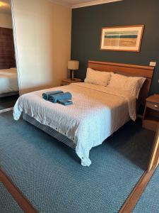 a bedroom with a bed with a blue towel on it at A-The Entrance Private Water Front 1 bedroom appartment at the Oaks in The Entrance