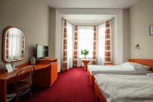 Habitación de hotel con 2 camas, escritorio y espejo. en Hotel Kazimierz II, en Cracovia