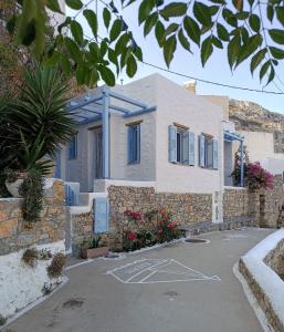 uma casa branca com janelas azuis e uma entrada em Villa Nina, dreamy little cycladic home in Amorgos em Órmos Aiyialís