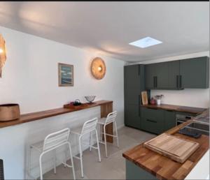 uma cozinha com armários verdes e um balcão com bancos em Jolie maison Pays d'Aix em Rognes