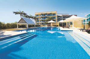 a large swimming pool with a hotel in the background at A-The Entrance Private Water Front 1 bedroom appartment at the Oaks in The Entrance