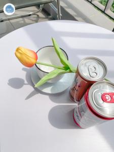 a tulip in a glass bowl and a can of soda at It Dust Homestay 1 - The Ocean Apartment in Hanoi