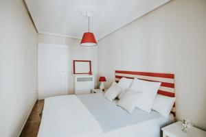 Dormitorio blanco con cama blanca y lámpara roja en 1880 HAROs OLD TOWN HOUSE en Haro