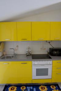 una cocina con armarios amarillos y fregadero en La Mansarda, en Marina di Gioiosa Ionica
