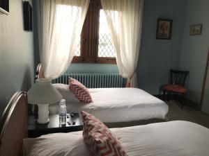 DOMAINE ST GERMER في Reilly: غرفة بسريرين وطاولة بها مصباح