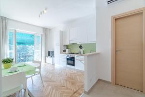 a kitchen with white cabinets and a table and a door at Asti Comfy Apartment - Private Parking! in Asti