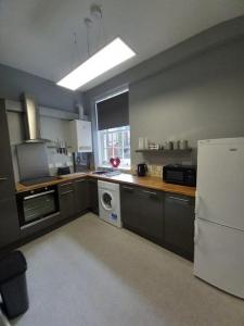 a kitchen with a white refrigerator and a dishwasher at The Nifty Nook in Campbeltown