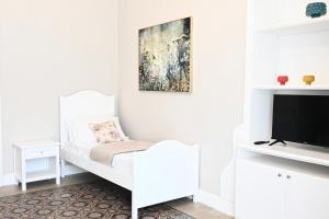 a white bedroom with a bed and a tv at Civico 10 Deluxe Room in Licata