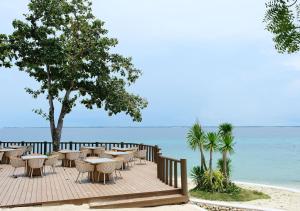 a wooden deck with tables and chairs on the beach at Belmont Hotel Mactan in Mactan