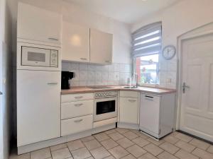 a kitchen with white cabinets and a white refrigerator at Ingrids Ferienwohnung in Erfde