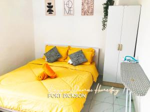 een slaapkamer met een bed met gele lakens en kussens bij Laguna Damai Homestay PortDickson - "PoolView & BeachNearby" in Port Dickson