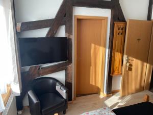 uma sala de estar com uma cadeira preta e uma televisão de ecrã plano em Hotel Klement em Zehdenick