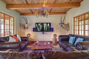 sala de estar con sofás de cuero y mesa en Buccara Wildlife Reserve, en Graaff-Reinet