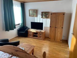 ein Wohnzimmer mit einem TV und einem Tisch in der Unterkunft Hotel Klement in Zehdenick