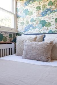 a bed with two pillows and a floral wall at The South Hampstead Collection in London