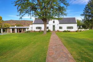 a white house with a tree in the yard at Buccara Wildlife Reserve in Graaff-Reinet