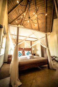 een slaapkamer met een hemelbed en een kroonluchter bij Onsea House & Machweo Retreat in Nkoanrua