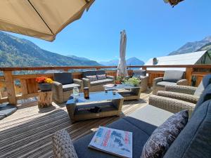 a deck with couches and tables and an umbrella at Chalet Augustin in Vaujany