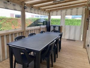 a black table and chairs on a wooden deck at - Mobilhome Camping Les Charmettes - Fun pass non inclus - in Les Mathes