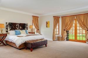 a bedroom with a bed and a table and windows at Buccara Wildlife Reserve in Graaff-Reinet