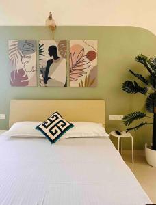 a bedroom with a bed with four paintings on the wall at Sage : Private Studio Room in Koregaon Park in Pune